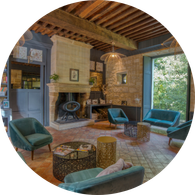 Le grand salon : poêle dans la cheminée Grande pièce qui peut selon vos envies servir de piste de danse ou bien de rester équipé de canapés et servir de coin détente. Les murs sont tous en pierres de savonnières, sol en tomette (sol chauffant). Une grande fenêtre vous permettra d’avoir une vue large sur notre parc arboré.